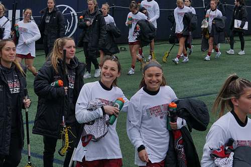 person women holding lacrosse sticks on green field people