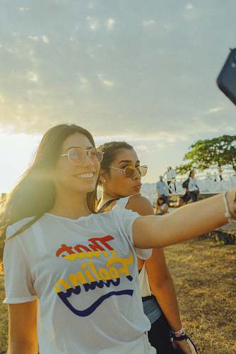 person women taking photo near beach at daytime people