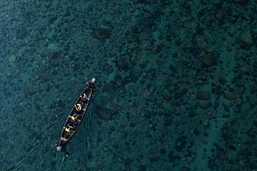 water aerial photo of canoe on calm water with people aerial view