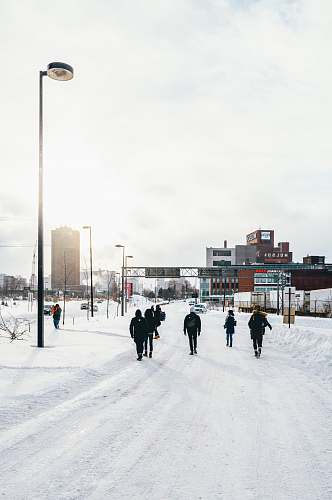 snow people walking on snow covered road during day time city