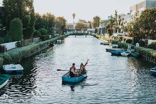 canal two person on blue boat during daytime water