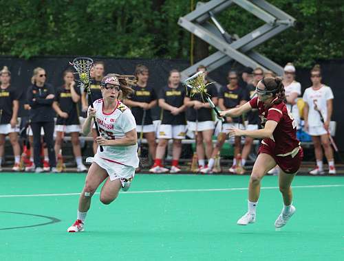human women playing lacrosse game during daytime sport