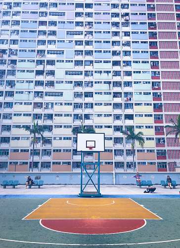 human basketball court in front of concrete high-rise building during daytime people
