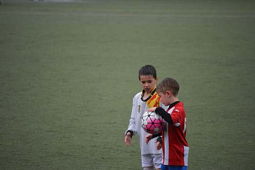 team boy holding soccer ball beside other ball on soccer field soccer