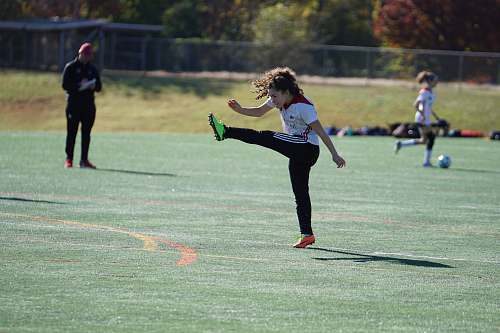 human girl kicking in air near girl and man holding white paper people