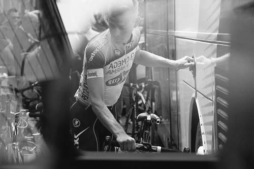 human grayscale photo of man holding bike black-and-white