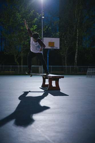 human man doing skateboard stunt on bench people