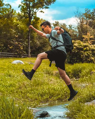 human man hop on the body of water through grass apparel