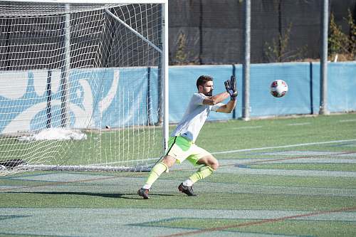 human man playing soccer during daytime football