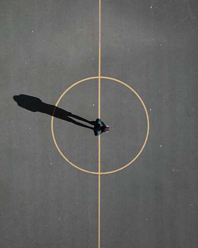 people man stainding on black concrete floor casting shadow basketball