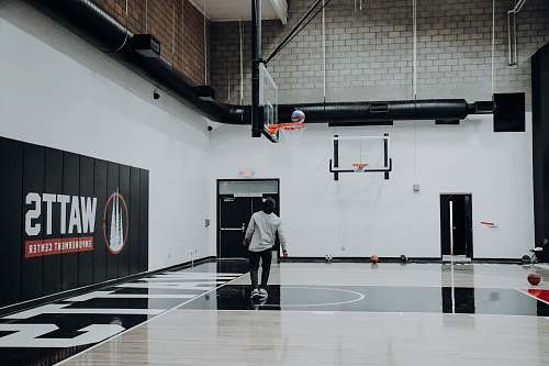 people man standing inside basketball court looking at ball on basketball hoop human