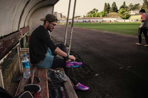 human man tying his shoes while sitting on bench bottle