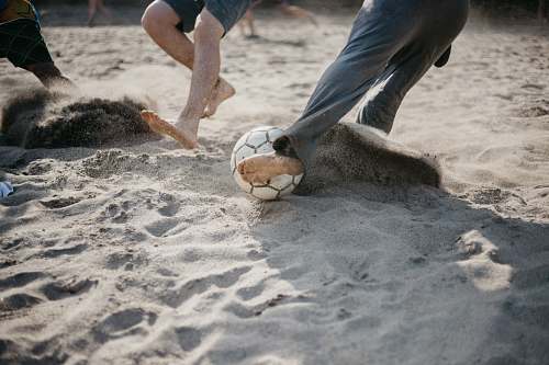 human people playing soccer on sand sphere