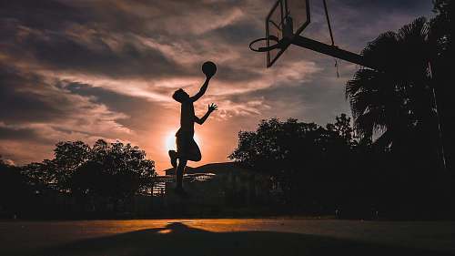 human silhouette of boy jumping shooting ball people