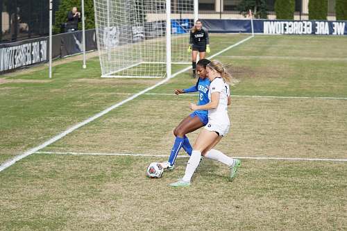 human two girls playing soccer during daytime people