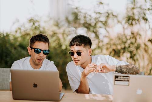 human two men using MacBooks people