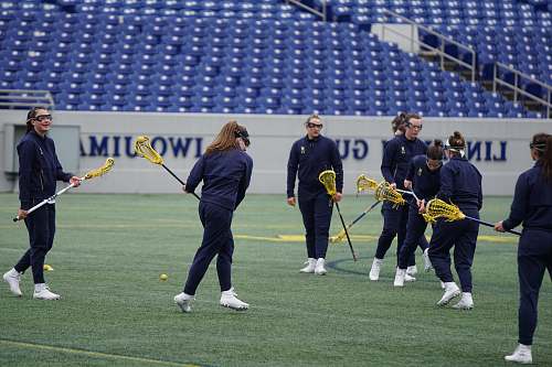human women playing lacrosse on field during daytime field