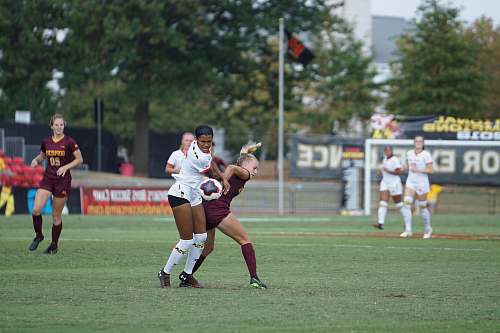 human women playing soccer at daytime people