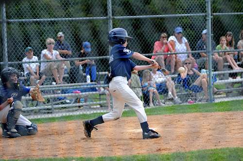 sports boy batting baseball near catcher beside gray fence baseball