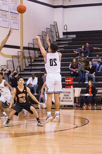 basketball man in white and black number 20 jersey shirt shooting a basketball gym