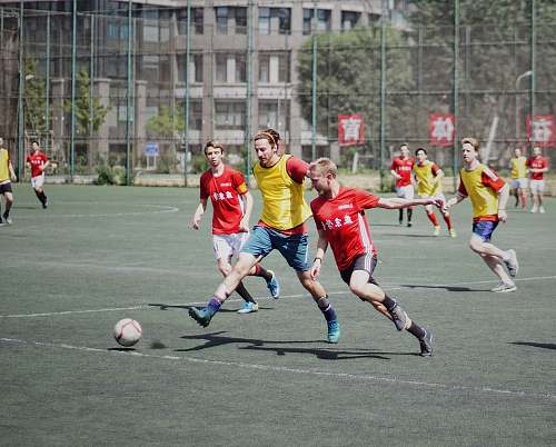football men playing soccer on field with fence team