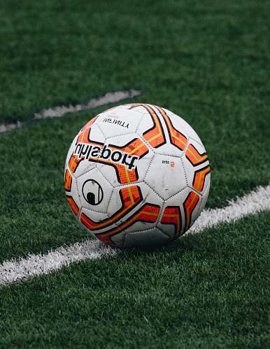 football red and orange soccer ball on green grass field soccer