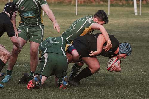 human rugby players tackling each other while on field person