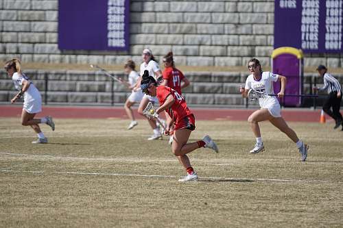 human women playing lacrosse at the open field person