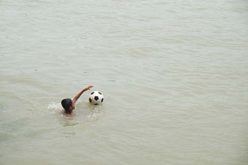 swimming boy playing on body of water with ball sports