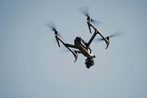 flying black drone on mid air bird