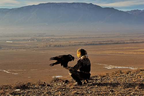bird person sitting beside eagle on hill vulture