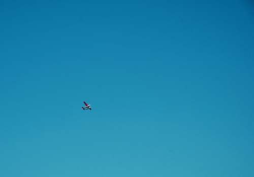 flying white plane under blue sky during daytime blue