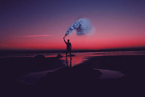 morocco silhouette of man standing on seashore holding smoke can smoke