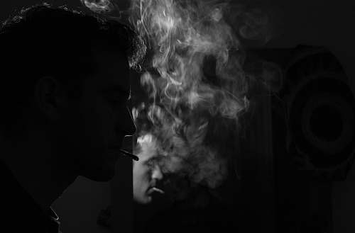 smoke grayscale photography of man smoking cigarette face