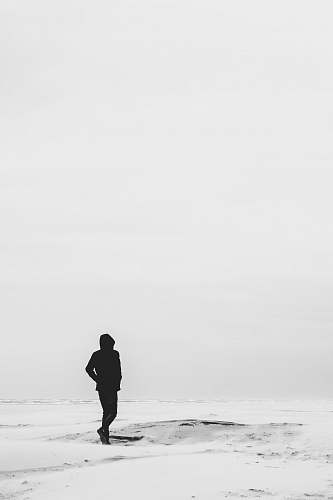 human man wearing hoodie standing on snow covered field during daytime person