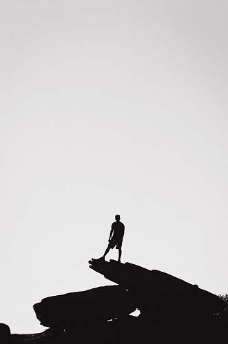 silhouette person standing in a rock formation grey-scale photography person