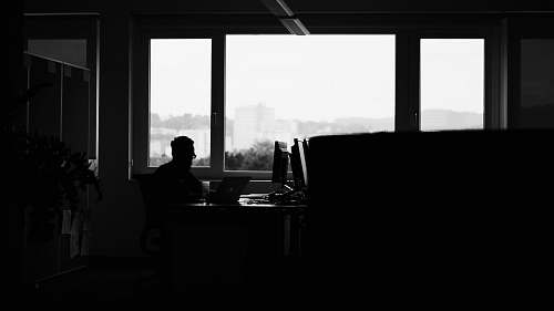 window silhouette of man sitting along glass window silhouette