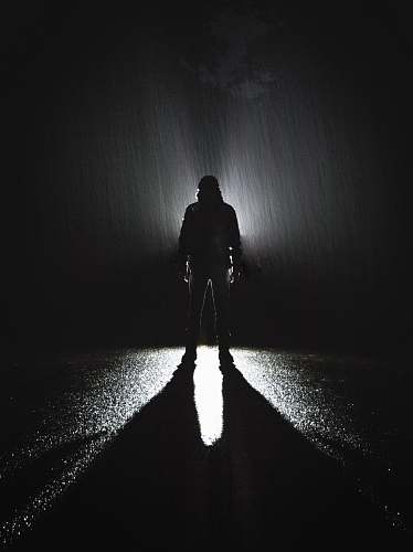 person silhouette of person standing on road during rain people