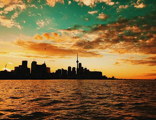 sunset body of water across city buildings during sunset dusk
