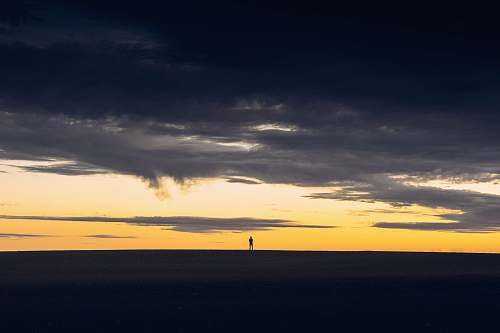 sunset silhouette of person standing on hill during sunset cloud