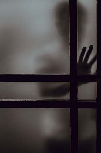 cross person touching frosted glass door dark