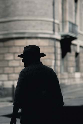cambridge silhouette photo of a man with hat standing near concrete building at daytime man