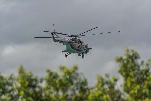 vehicle green helicopter flying under cloudy sky transportation