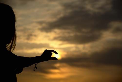 nature forced perspective photography of woman holding sun outdoors