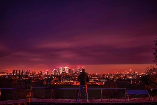 person man standing and facing city during night time nature