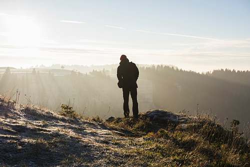 person man standing on cliff near trees during daytime people