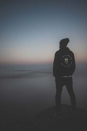 grey man standing on peak at daytime standing