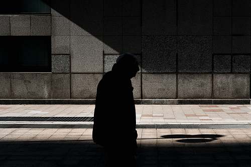 person man walking on street under shade of sun during daytime pedestrian