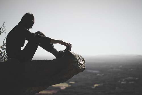 person person sitting on cliff silhouette