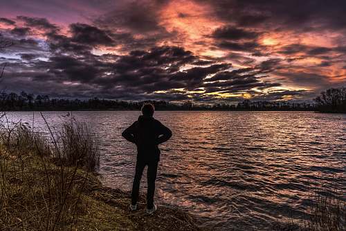 person person standing near body of water during golden hour people